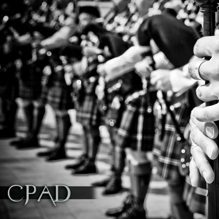 Ein Nahaufnahme von Dudelsackspielern in Kilts, die in einer Reihe stehen, ihre Instrumente halten und schwarze Mützen tragen.
