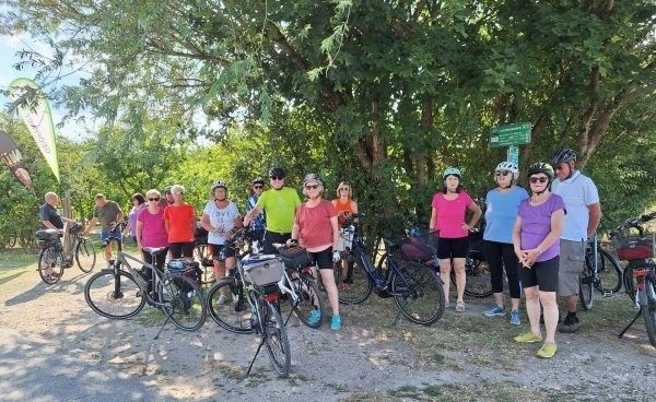 Eine Gruppe von Menschen in Helmen und Fahrradausrüstung posiert für ein Foto in einem Waldgebiet mit Fahrrädern und Bäumen.