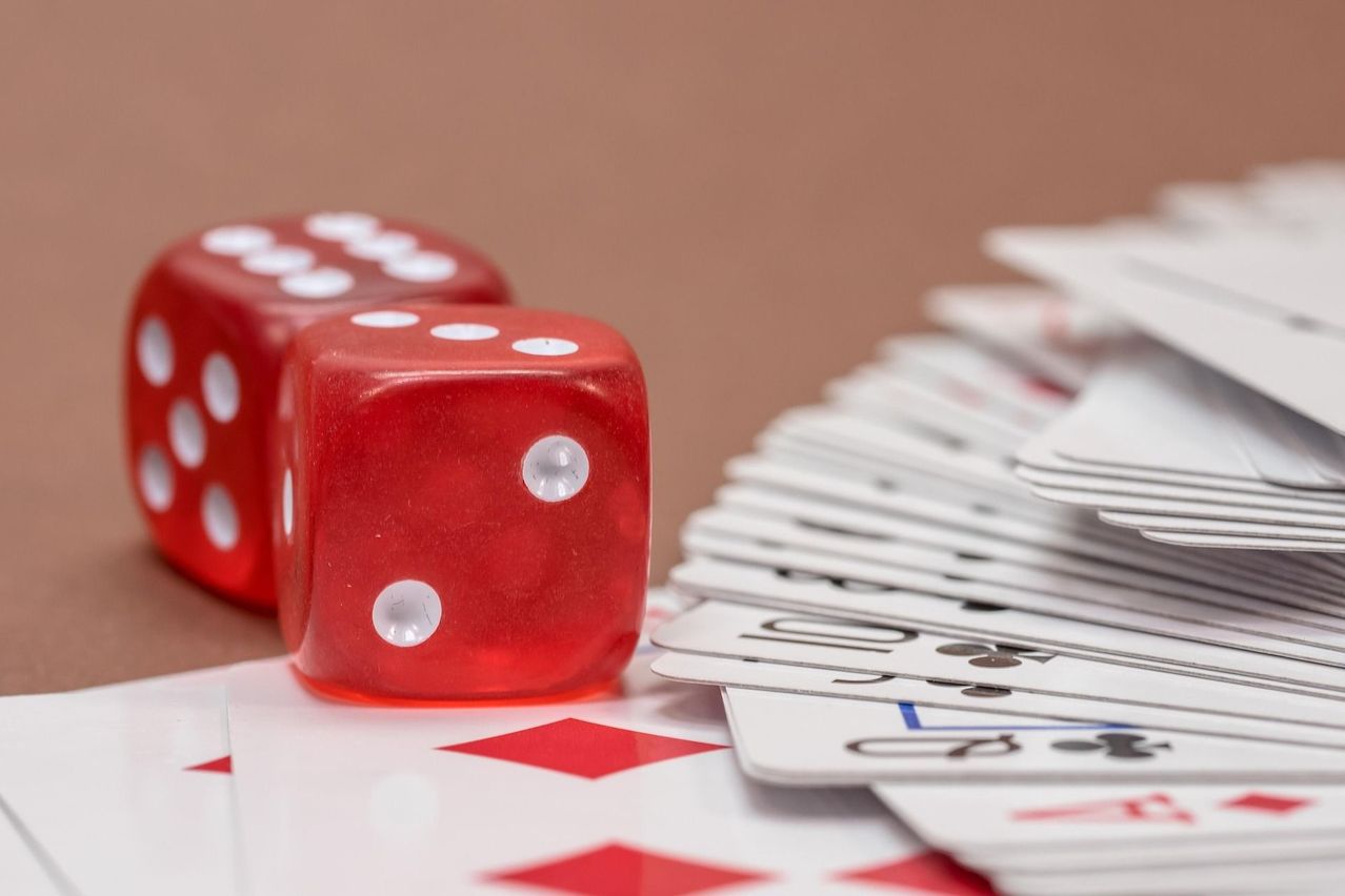 Eine Nahaufnahme von zwei roten Würfeln und einem Kartenspiel, einschließlich der Zahl zehn, auf einem Tisch.