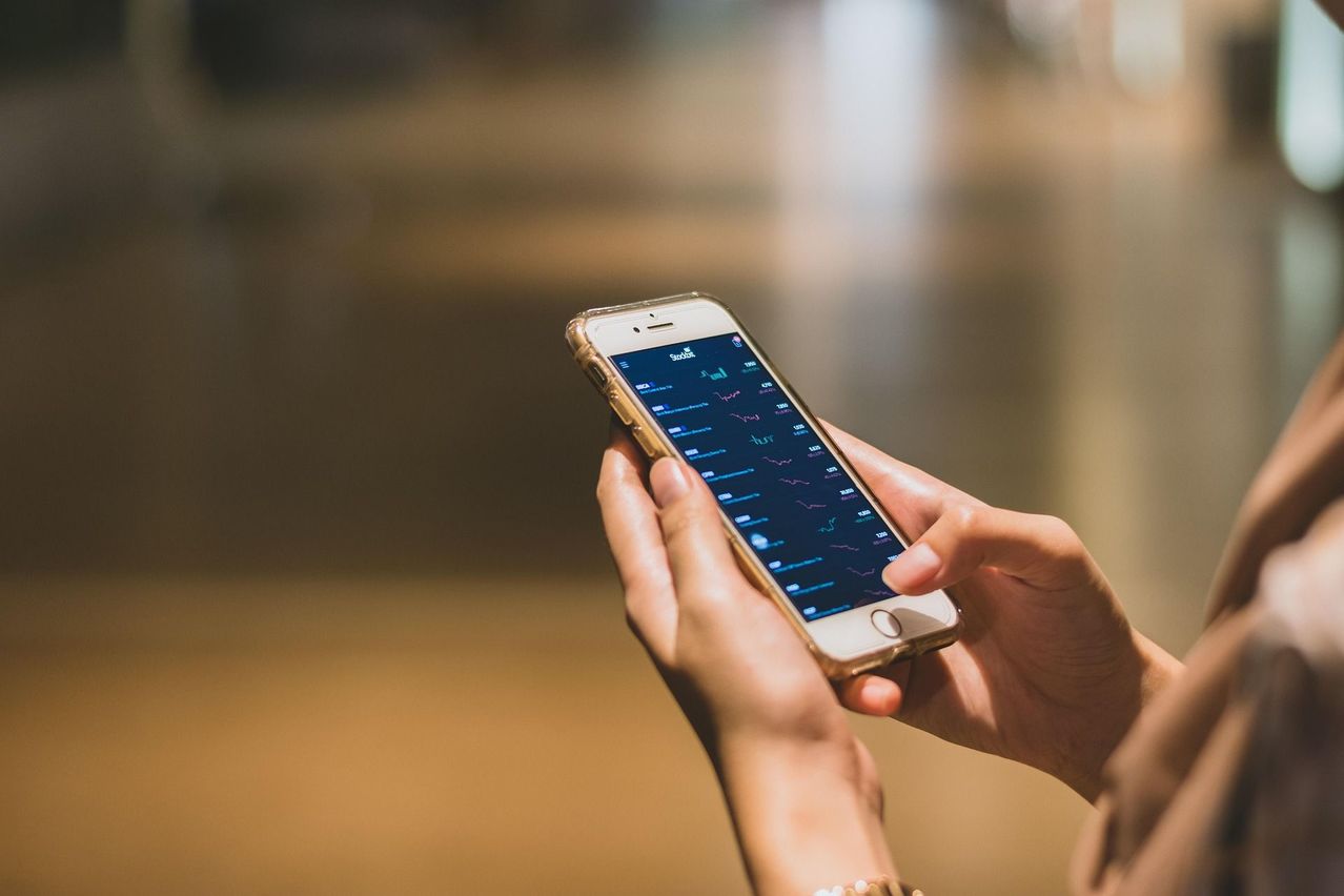 Eine Person hält ein Smartphone mit einer Finanz-App auf dem Bildschirm, die Aktienmarktdaten anzeigt.