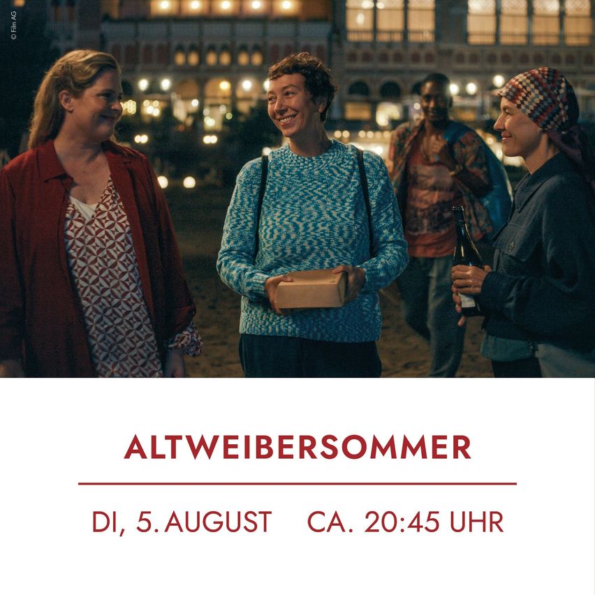 Vier Menschen stehen bei Nacht draußen. Eine Frau links lächelt, hält eine Box und trägt einen roten Mantel. Eine andere Frau rechts hält eine Flasche und trägt ein kariertes Kopftuch. Der Hintergrund ist unscharf, mit Gebäuden und Lichtern.