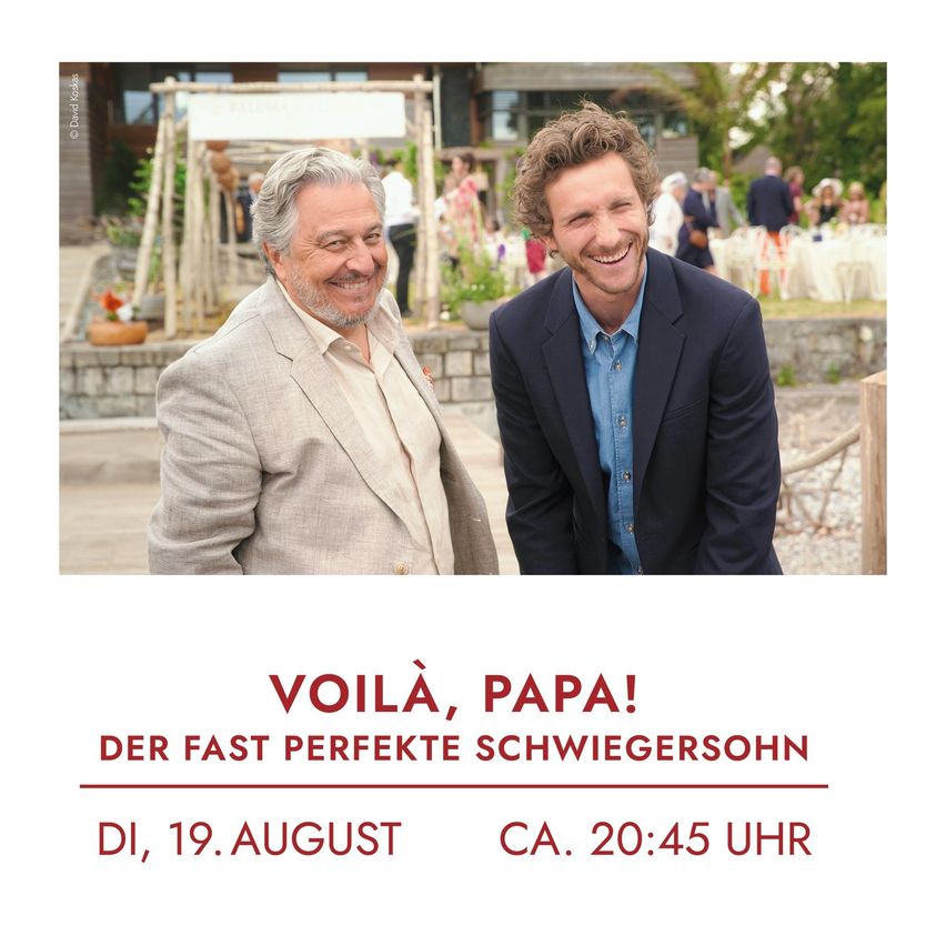 Zwei lächelnde Männer, wahrscheinlich Schauspieler, mit einem Hochzeitsaufbau im Hintergrund. Der Text lautet 'VOILA, PAPA!' und 'Der Fast Perfekte Schwiegersohn'. Unten ein Datum und eine Uhrzeit: Dienstag, 19. August, ungefähr 20:45 Uhr.