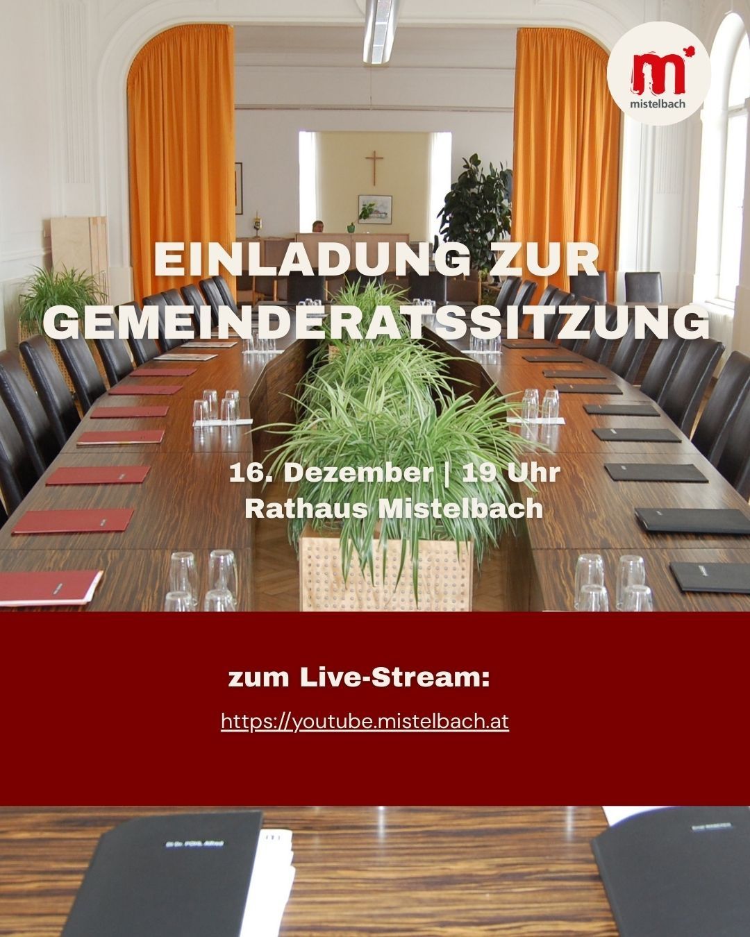 Ein Bild eines Konferenzraums mit einem Tisch und Stühlen, einem Topf mit Pflanzen und einem Schild mit der Aufschrift 'Einladung zur Gemeinderatssitzung' mit Datum und Uhrzeit.