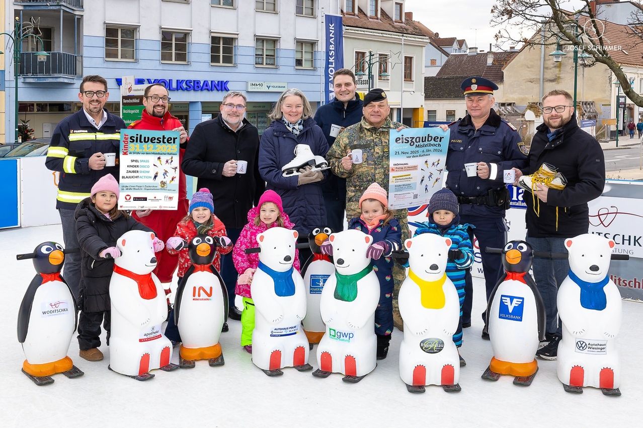 Eine Gruppe von Erwachsenen und Kindern in Winterkleidung posiert für ein Foto auf einer Eisbahn mit Eisbär-Skulpturen. Erwachsene halten Schilder und Tassen.