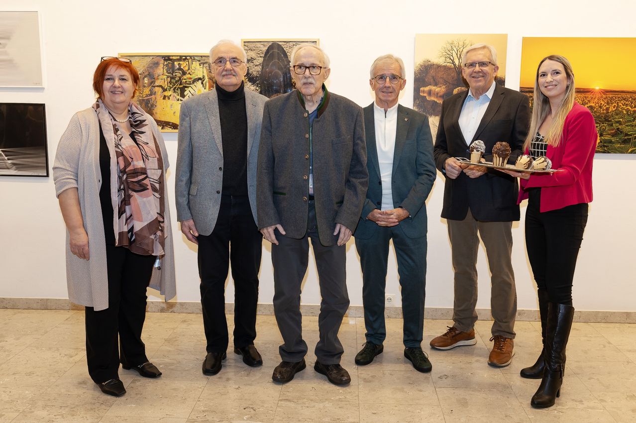 A group of six people stands in front of an art gallery. The man on the far right holds a tray with ice cream.