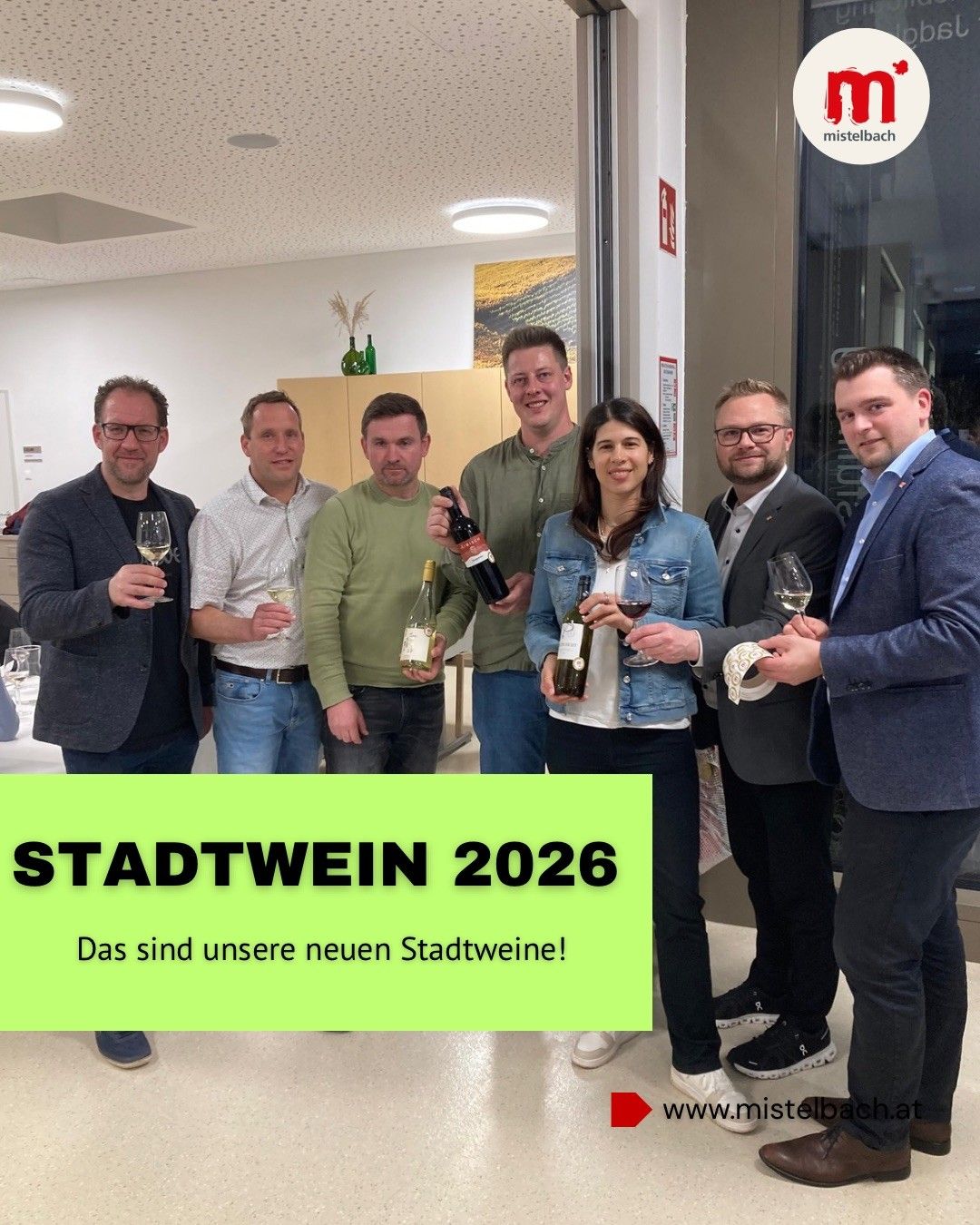 Gruppe von Menschen, die zusammenstehen und Weingläser und Flaschen halten. Der Mann auf der linken Seite hält ein Glas, während die anderen Weinflaschen halten. Sie alle lächeln und scheinen für ein Foto zu posieren.