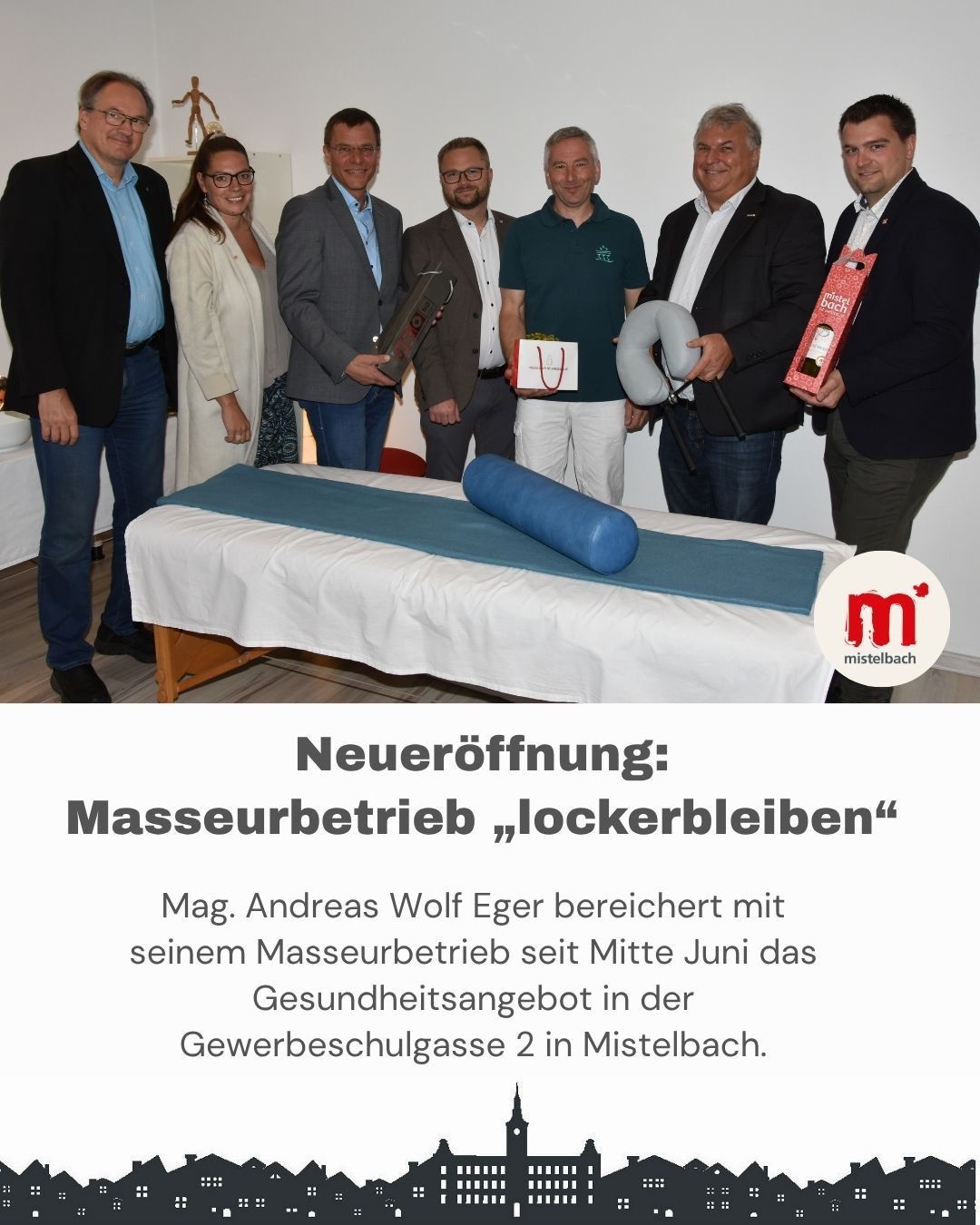 Eine Gruppe von Personen posiert für ein Foto in einem Raum mit einem Massagetisch. Sie halten verschiedene Gegenstände und Geschenke. Die Bildunterschrift sagt 'Neue Eröffnung: Massagestudio Lockerbleiben'. Der Standort ist Gewerbeschulgasse 2 in Mistelbach.