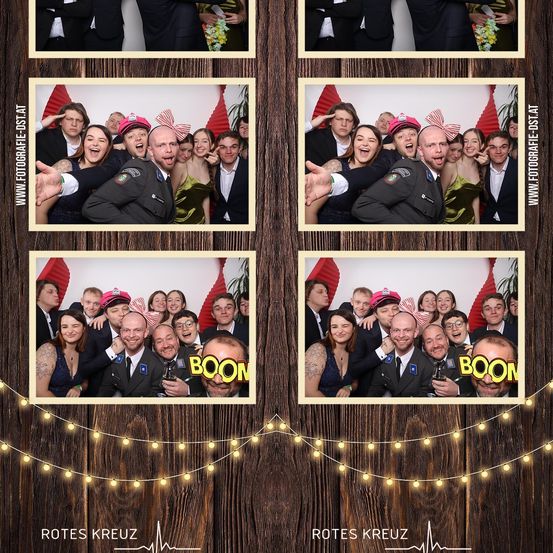 Vier Fotokabinenbilder, die in einem Raster auf einem hölzernen Hintergrund angeordnet sind. Jedes Foto zeigt eine Gruppe von Menschen, einige in Militäruniformen, alle lächelnd und posierend. Das Wort 'BOOM' erscheint unten rechts auf zwei Fotos. Ein Wasserzeichen ist unten sichtbar.