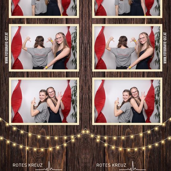 Eine Fotocollage zeigt vier Bilder von zwei Frauen in einem Fotokabinen mit rotem Hintergrund. Jedes Foto zeigt verschiedene Posen und Ausdrücke.