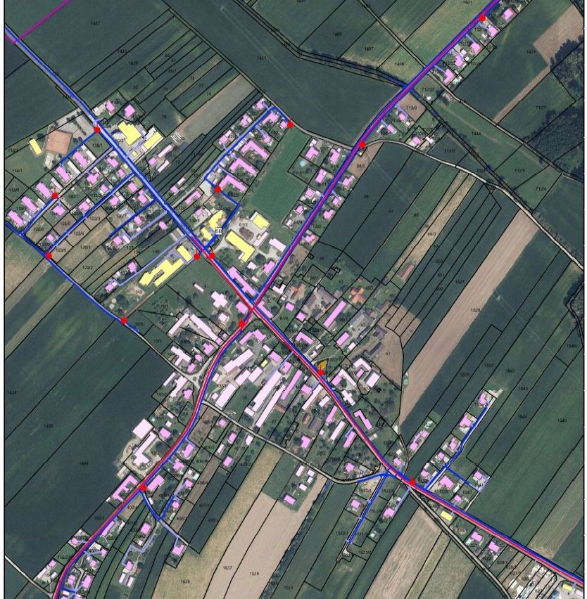 Eine Satellitenaufnahme einer Stadt mit Gebäuden, Straßen und Feldern. Die Stadt hat verschiedene Strukturen, einschließlich Häuser, die durch Straßen verbunden sind. Das Gebiet ist von grünen Feldern umgeben.