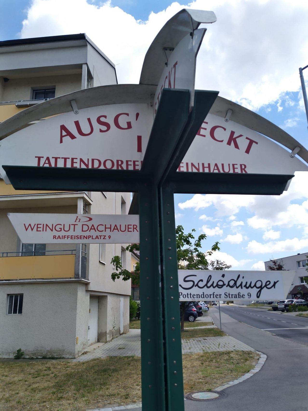 A street sign for Tattendorf in Austria. It includes directions for Weingut Dachauer and Schödinger Pottendorfer Straße.