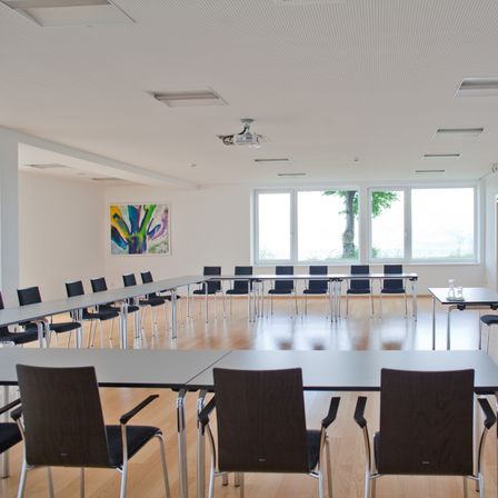 Bild enthält, Indoors, Chair, Furniture, Meeting Room, Office, Room, Interior Design, Desk, Building, Cup