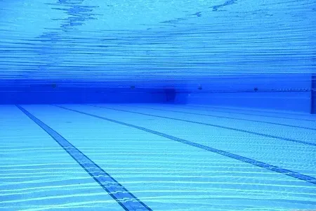 Ein Schwimmbecken mit blauem Wasser und Bahnlinien. Das Becken ist leer und mit blauen Lichtern beleuchtet.