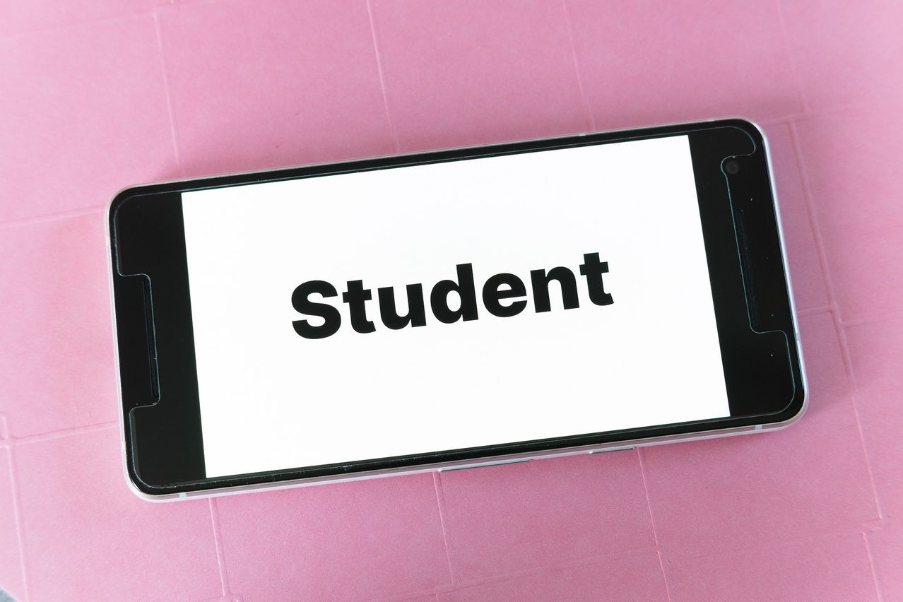 A smartphone displaying the word 'Student' on its screen, set against a pink background.