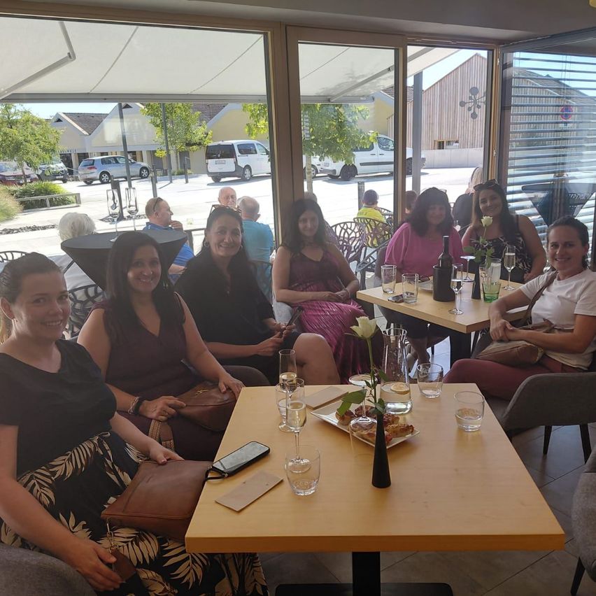 Eine Gruppe von Frauen sitzt an einem Tisch in einem Restaurant mit Blick nach draußen.