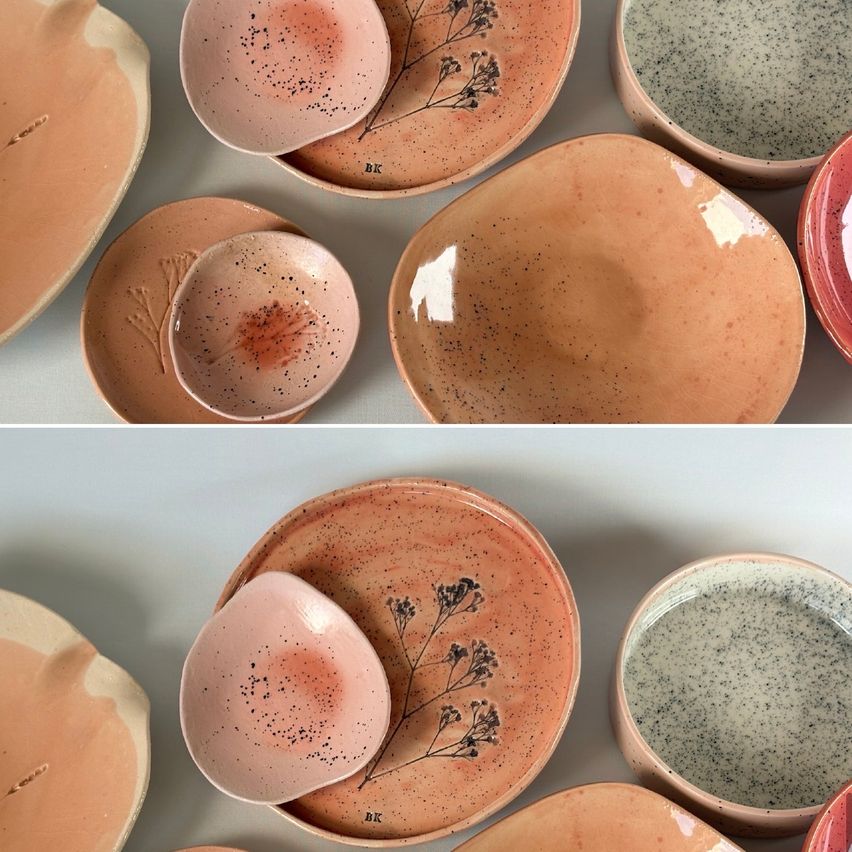 A collection of handmade ceramic plates and bowls with various designs and colors, including floral patterns and speckled glazes, displayed on a white surface.