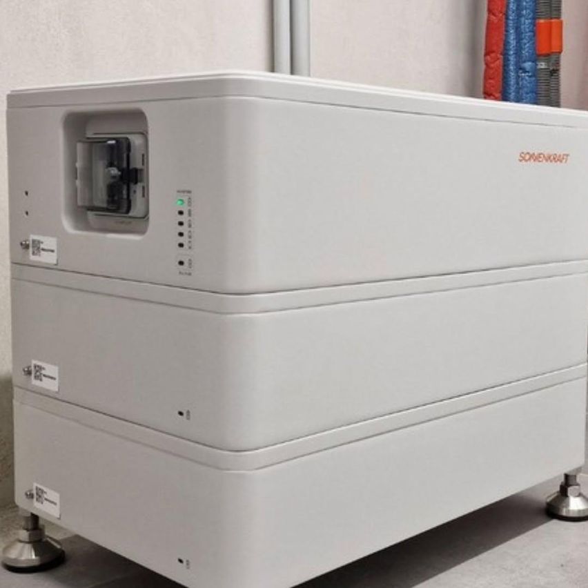 A white industrial machine with multiple compartments and a small window, labeled 'SOMENVO4F', sits on a grey floor.