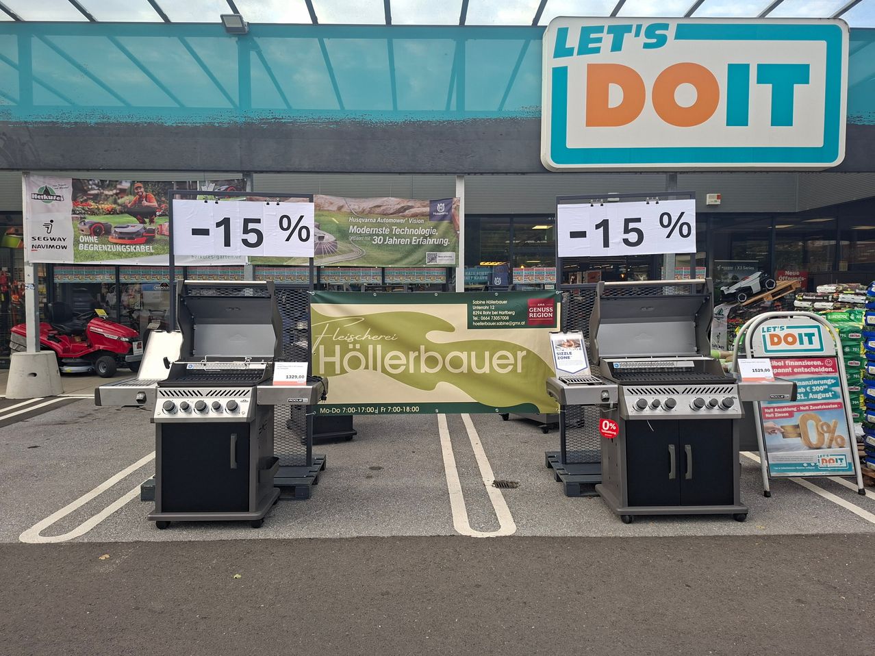 Grills im Freien im Angebot in einem Geschäft mit Rabattschild und Banner für Fleischerei Hollerbauer.
