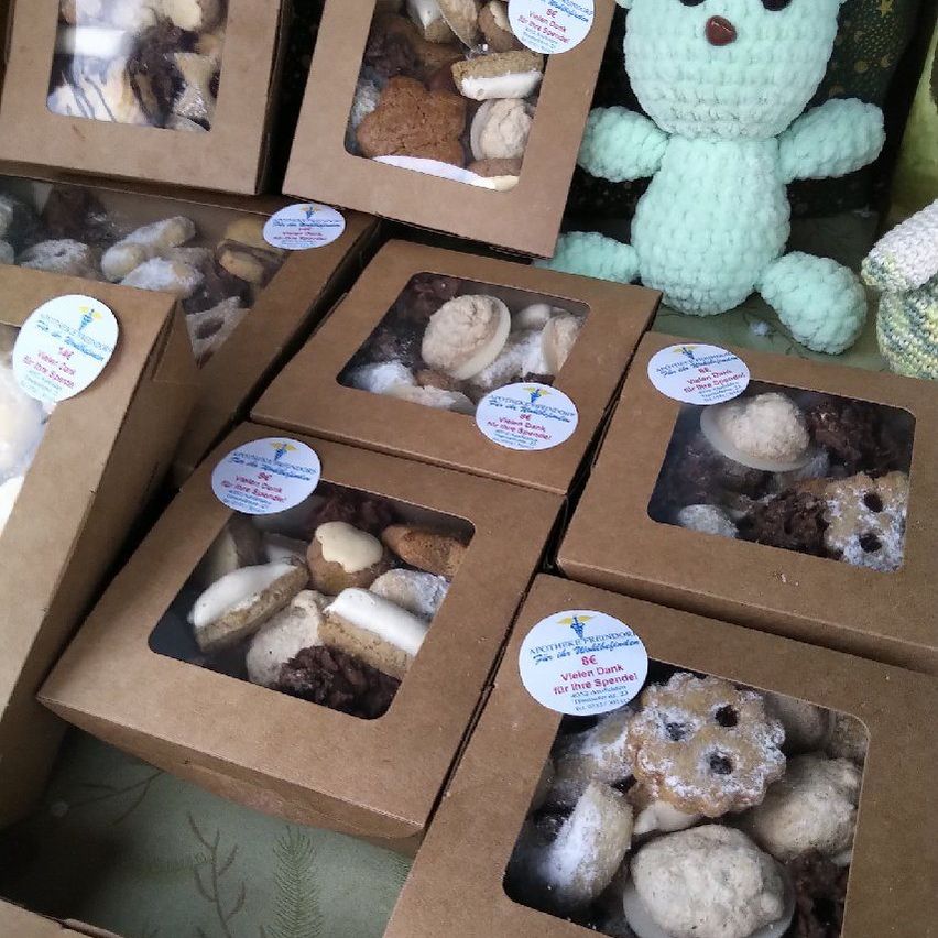 Several brown boxes of assorted cookies, including chocolate chip, are displayed. One box has a blue sticker with white text. A blue crocheted bear is on the right.