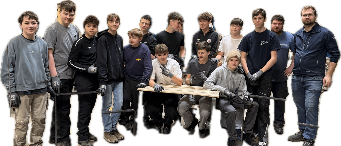 Eine Gruppe junger Männer steht und sitzt um einen Holztisch herum, alle tragen Handschuhe. Sie scheinen an einer Art manueller Aktivität beteiligt zu sein.