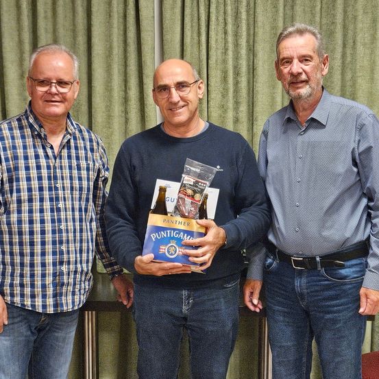 Drei Männer stehen zusammen, einer hält eine Panther Puntigam Bierbox. Sie lächeln und scheinen sich bei einer Veranstaltung zu befinden.