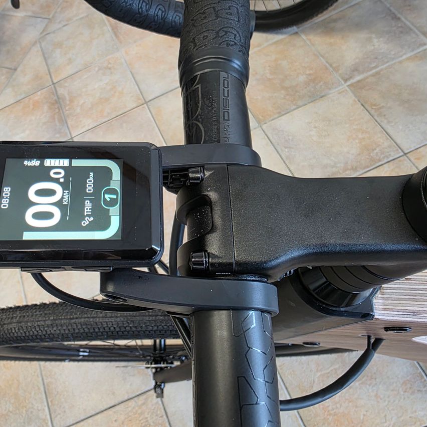 Nahaufnahme eines Fahrradlenkers mit einem digitalen Display, das '00.0' und '0 km/h' anzeigt. Der Lenker ist schwarz mit einem strukturierten Griff.