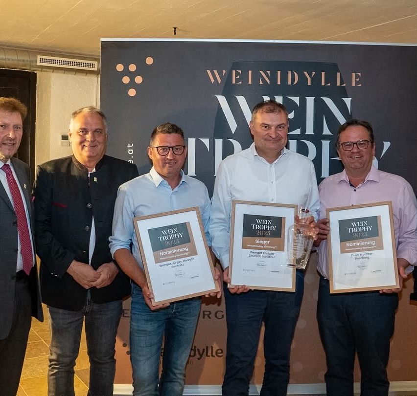 Fünf Männer stehen nebeneinander mit Auszeichnungen in den Händen. Der Mann in der Mitte hält eine Flasche Wein.