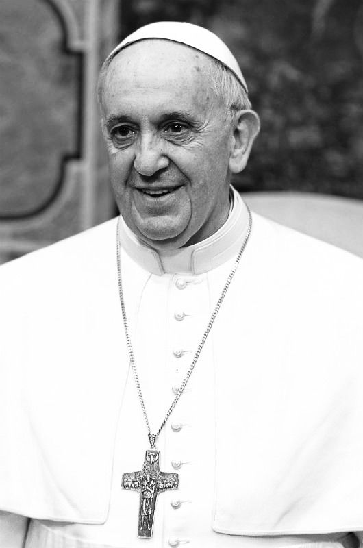 Schwarz-Weiß-Foto von Papst Franziskus. Er trägt eine weiße Robe, einen weißen Papsthut und eine Kreuzkette.
