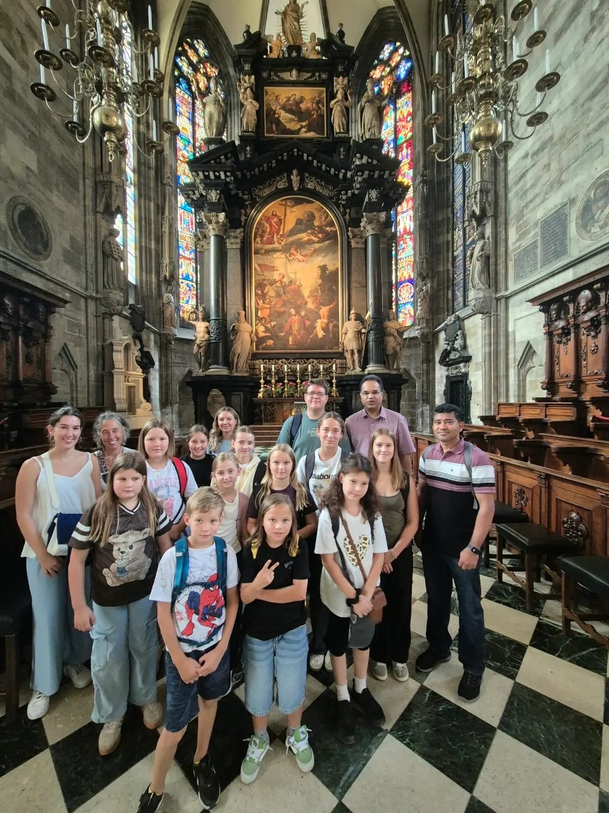 Eine Gruppe von Menschen, einschließlich Kindern, posiert für ein Foto in einer Kirche mit Buntglasfenstern und einem großen Altar.