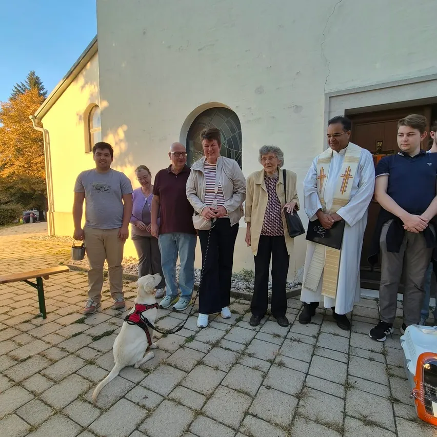 Eine Gruppe von Menschen und ein Hund stehen vor einer Kirche.