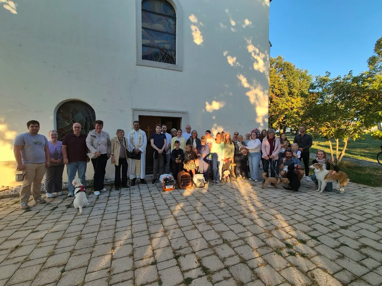 Eine Gruppe von Menschen und Hunden posiert für ein Foto vor einer Kirche.