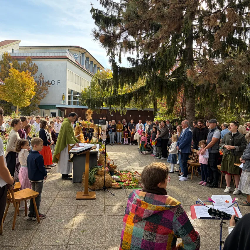 Ein Priester leitet eine religiöse Zeremonie im Freien, umgeben von einer großen Menschenmenge.