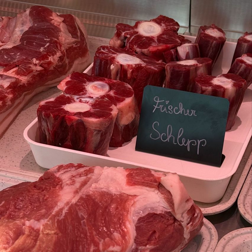 Eine Anzeige mit rohen Rindfleischstücken, einschließlich Rumpsteak, steht auf weißen Tabletts mit einem Schild, das Fuchscher Schlepp steht.