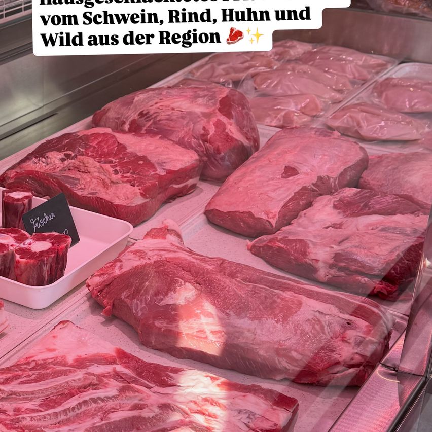 Eine Anzeige von frischem Fleisch von Schweinen, Rindern, Hühnern und Wildtieren. Das Fleisch ist ordentlich auf einem Tresen angeordnet, einige Stücke in einem Tablett.