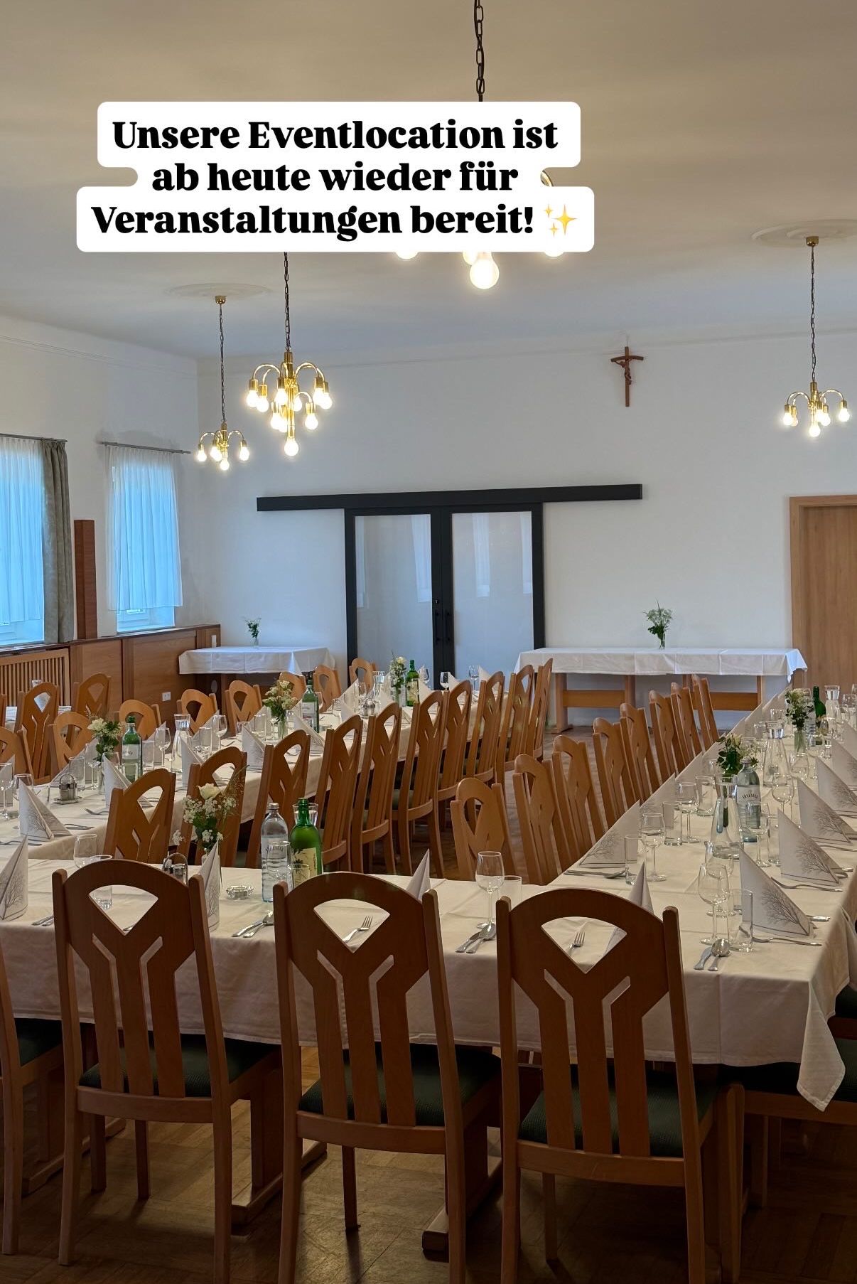 Ein Bankettsaal ist mit Tischen und Stühlen eingerichtet, geschmückt mit Blumen und Weingläsern, bereit für eine Veranstaltung.