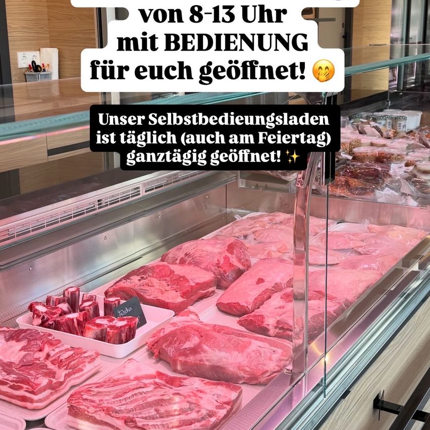 Eine Fleischtheke in einem Geschäft. Sie enthält verschiedene Stücke rohes Fleisch, in Plastik verpackt. Ein Overlay hat eine Nachricht, dass es den ganzen Tag geöffnet ist, auch an Feiertagen.