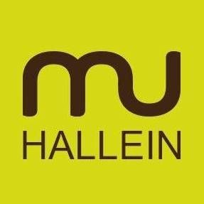 Das Logo für Hallein ist auf einem grünen Hintergrund dargestellt. Das Wort 'Hallein' ist in großgeschriebenem, fetter Schrift, während 'mu' in einer einzigartigen kursiven Schrift stilisiert ist.