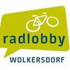 Die grüne Sprechblase enthält ein weißes Fahrrad-Symbol mit dem Wort 'radlobby' in blauer Schrift oben und 'WOLKERSDORF' in schwarzer Schrift unten.