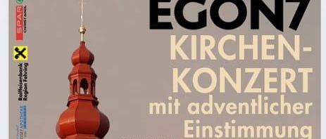 Plakat für Egon7 Kirchen Konzert mit adventlicher Einstimmung. Das Plakat zeigt eine Kirche mit einem roten Turm, einer Uhr und einem Gebäude mit geparkten Autos davor. Im Vordergrund sind zwei Personen zu sehen, eine Frau und ein Mann, die beide in die Kamera schauen. Die Veranstaltung findet am Sonntag, 23. November, um 16:00 Uhr statt.