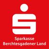 Der rote Hintergrund zeigt das Logo der Sparkasse Berchtesgadener Land mit einem stilisierten 'S' und einem Kreis darüber. Darunter stehen die Worte 'Sparkasse Berchtesgadener Land' in Weiß geschrieben.