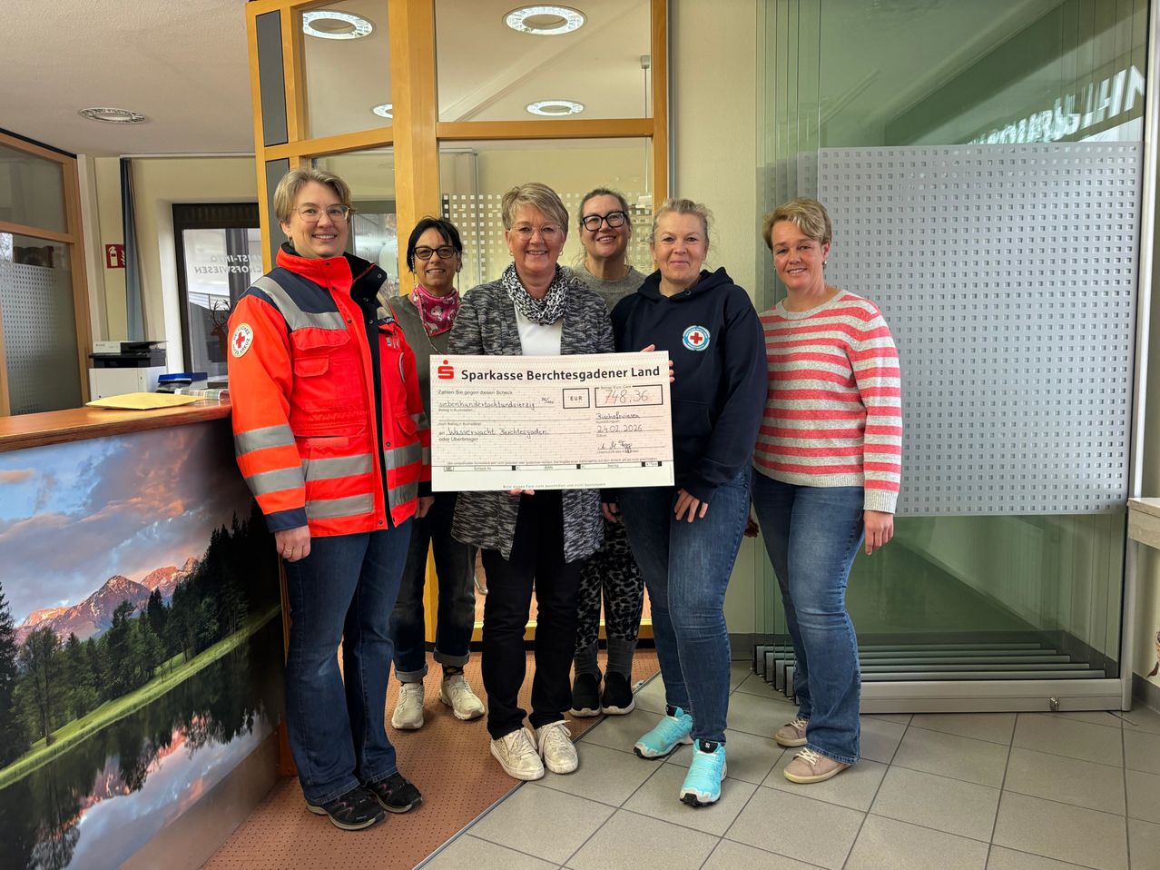 Sechs Frauen posieren für ein Foto mit einem großen Scheck von der Sparkasse Berchtesgadener Land. Sie stehen in einer Reihe, lächeln und eine hält den Scheck. Der Scheck hat einen beträchtlichen Betrag von 748,36 Euro.