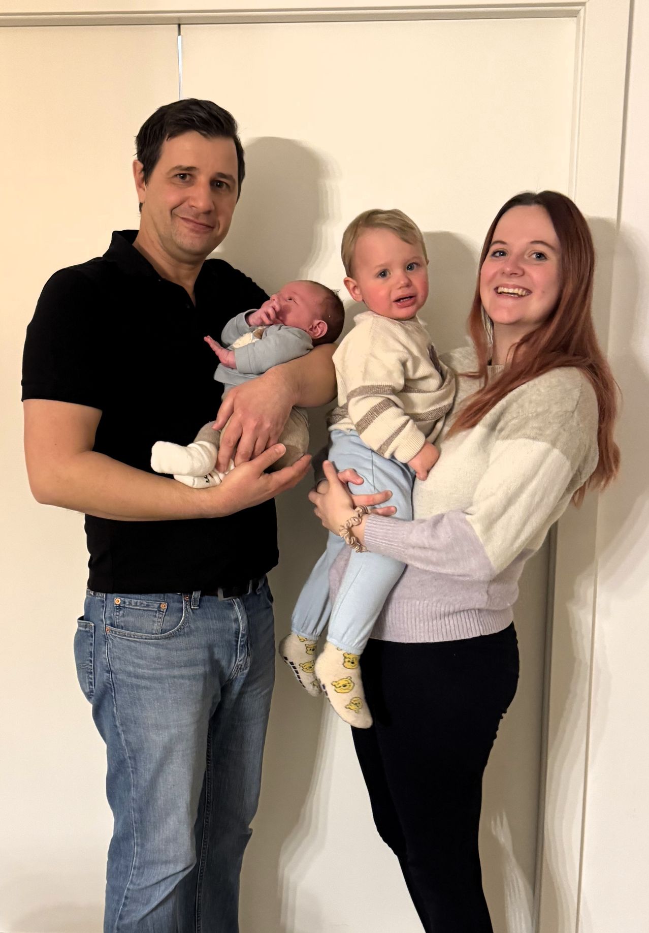 Ein Mann und eine Frau halten zwei Kinder. Ein Kind wird vom Mann und das andere von der Frau gehalten. Sie alle lächeln.