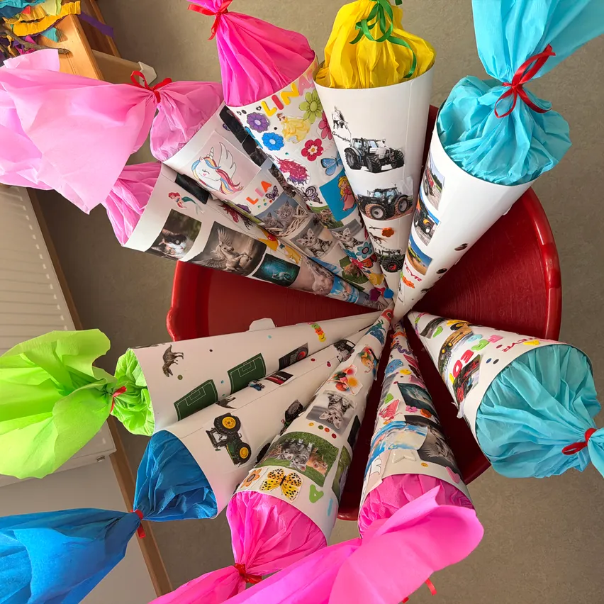 Eine Sammlung von farbenfrohen Papierkegeln mit verschiedenen Bildern darauf, in verschiedene farbige Papiere gewickelt und mit Bändern gebunden, auf einer roten kreisförmigen Oberfläche platziert.