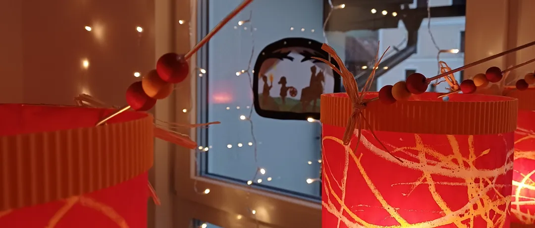 Zwei rote Laternen mit aufwendigen Mustern stehen auf einem Tisch und werden von einem warmen Licht erhellt. Sie sind mit Perlen verziert und haben eine festliche Atmosphäre.