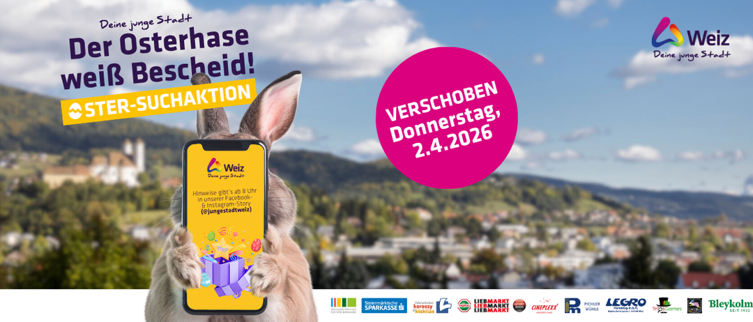 Ein Hase hält ein Telefon mit einem Geschenkkasten. Links steht 'Junge Stadt'. Rechts steht 'VERSCHOEBEN DONNERSTAG 2.4.2026'. Der Hase ist in der Nähe eines Gebirgszuges und einer Stadt.