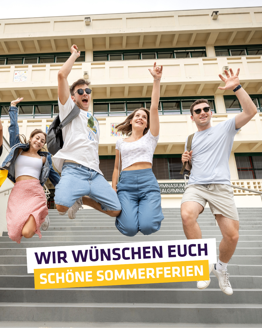 Vier Personen springen vor einem Gebäude auf einer Treppe, tragen Freizeitkleidung und lächeln. Der Text lautet 'Wir wünschen euch schöne Sommerferien'.