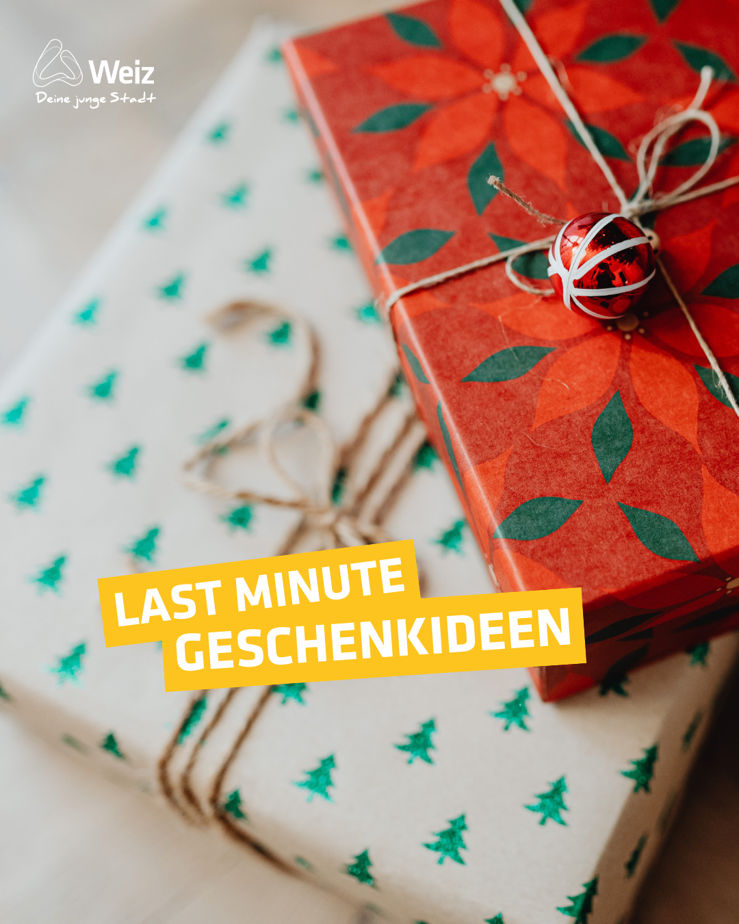 Eine Nahaufnahme eines roten Geschenkkartons mit rotem Poinsettia-Design, mit einem braunen Band gebunden und einer kleinen roten Kugel oben drauf. Das Geschenk liegt auf einem weißen Geschenkkarton mit grünen Weihnachtsbaum-Designs. Der Text lautet 'Last Minute Geschenkideen'.