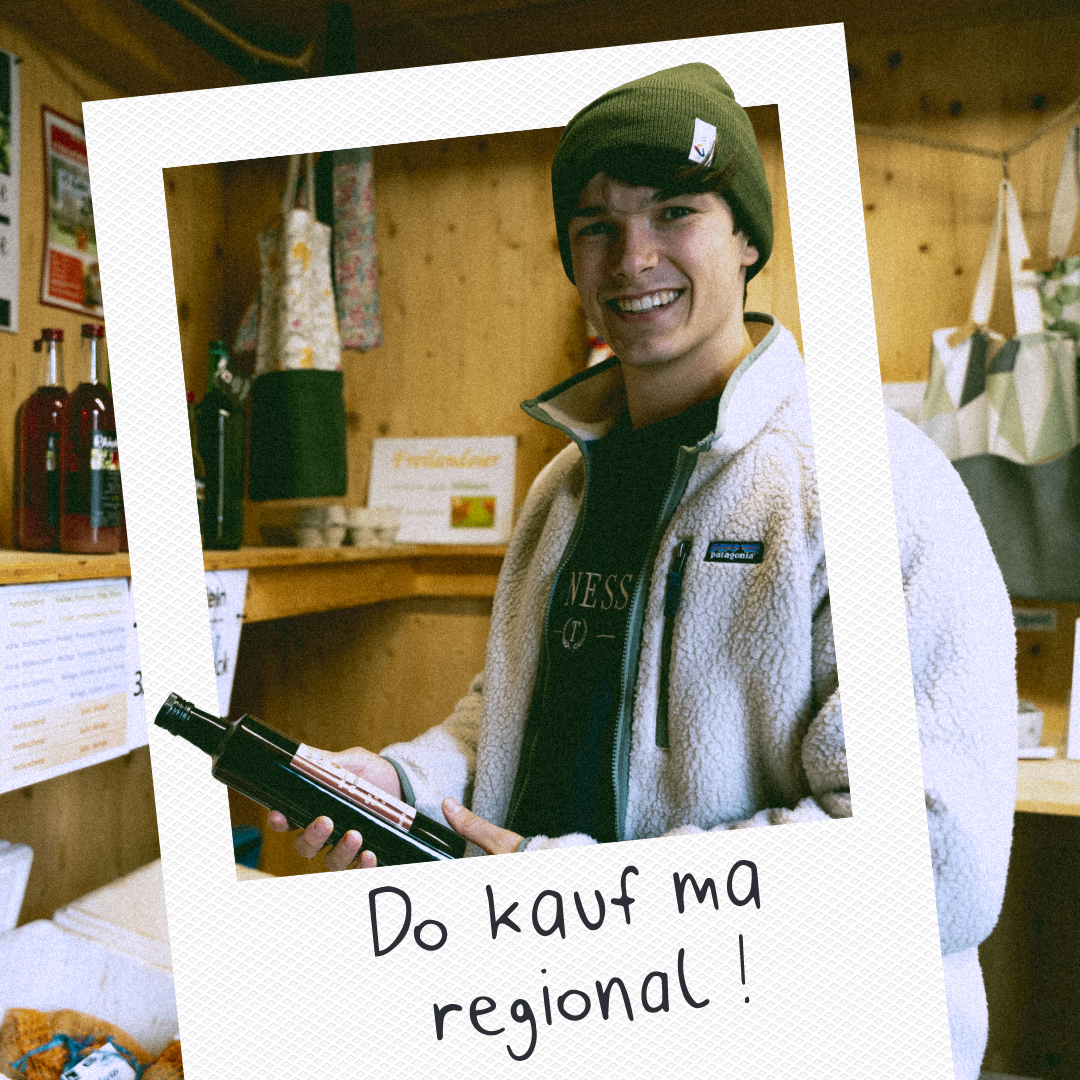 Ein junger Mann mit grüner Mütze hält eine Weinflasche in einem rustikalen Laden, umgeben von Holzregalen mit Produkten und Taschen. Der Text 'Do kauf ma regional!' deutet auf den Kauf regionaler Produkte hin.