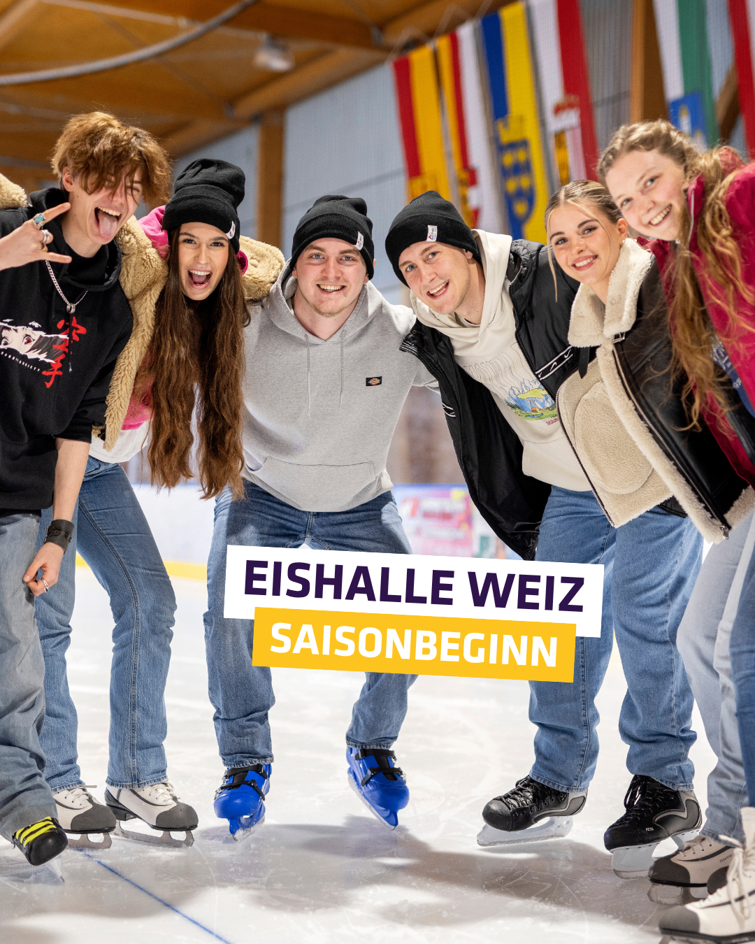 Eine Gruppe von Menschen posiert für ein Foto auf einer Eisbahn. Sie tragen alle Winterkleidung und Schlittschuhe. Ein Banner mit Text in der Mitte besagt 'EISHALLE WEIZ SAISONBEGINN'.