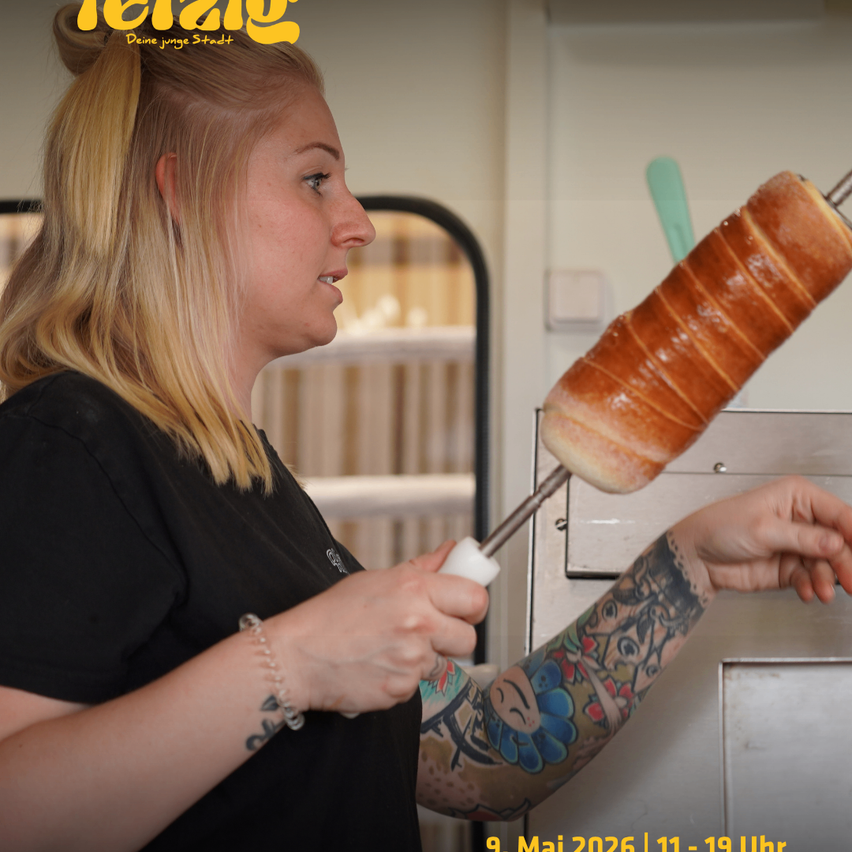 Eine Frau mit Tätowierungen hält ein Werkzeug mit einem Brötchen. Das Datum und die Uhrzeit sind 9. Mai 2026, 11:19 Uhr.
